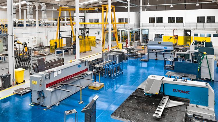 A modern factory floor: machines arranged for the work, each with its own motor, no central spindle, no overhead shafts and belts. The geometry of the building reorganized around what electricity actually was.